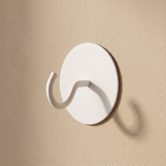 Weißer runder Klebehaken aus Edelstahl an warm-beiger Wand
