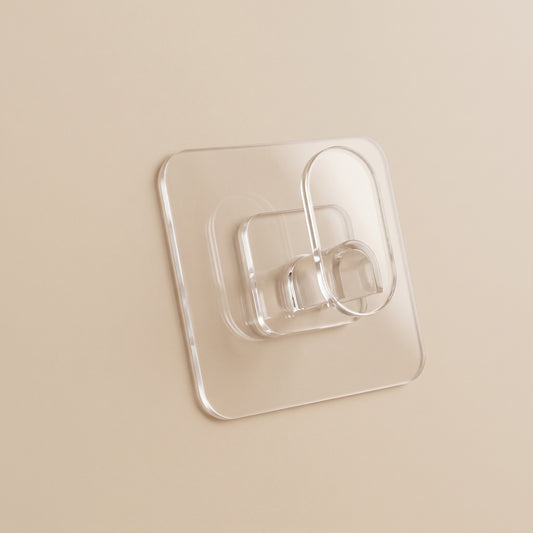 Transparenter Klebehaken groß an glatter, warm-beiger Wand, klare Klebeplatte und ovaler Bügel
